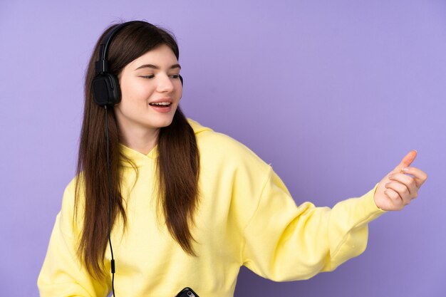 Jonge Oekraïense tienervrouw over geïsoleerde purpere muur het luisteren muziek en het doen van gitaargebaar