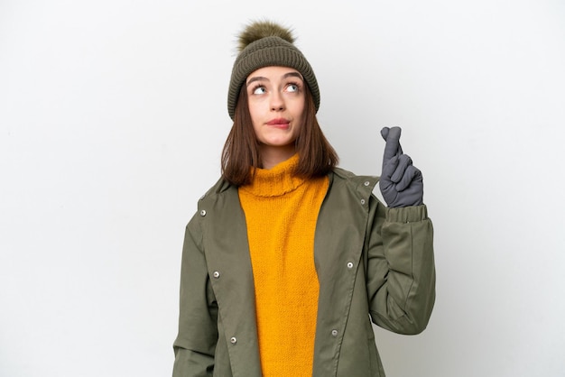 Jonge Oekraïense vrouw draagt winterjas geïsoleerd op een witte achtergrond met vingers die kruisen en het beste wensen