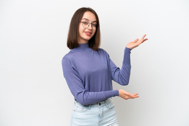 Jonge Oekraïense vrouw geïsoleerd op een witte achtergrond die haar handen naar de zijkant uitstrekt om uit te nodigen om te komen