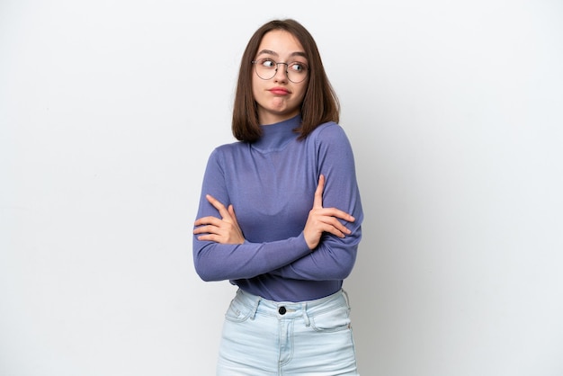 Jonge Oekraïense vrouw geïsoleerd op een witte achtergrond die twijfels gebaar maakt terwijl ze de schouders opheft