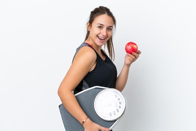 Jonge Oekraïense vrouw geïsoleerd op een witte achtergrond met weegmachine en met een apple