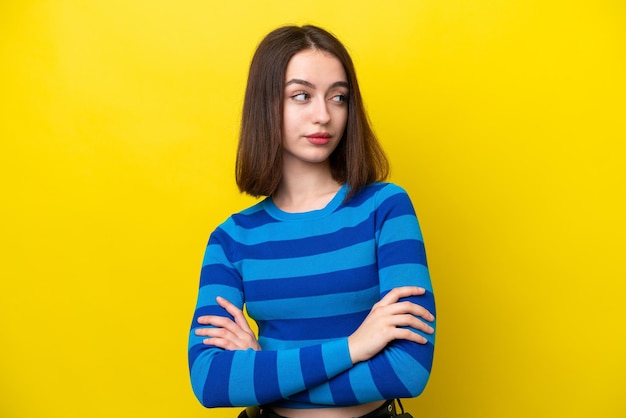 Jonge Oekraïense vrouw geïsoleerd op gele achtergrond die de armen gekruist houdt