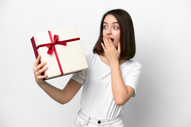 Jonge Oekraïense vrouw met een geschenk geïsoleerd op een witte achtergrond met verrassing en geschokte gezichtsuitdrukking