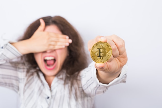 Foto jonge onderneemster die een gouden bitcoin houdt