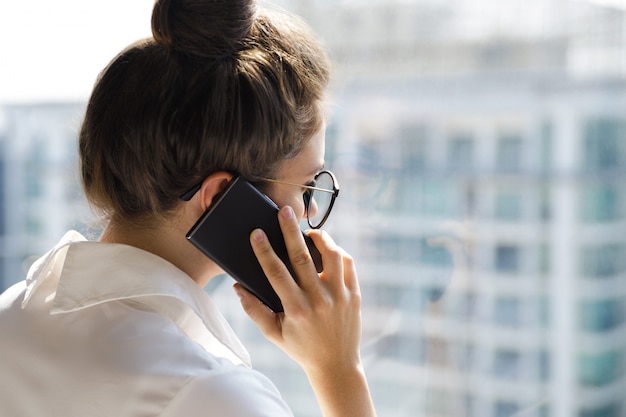 Jonge onderneemster die smartphone in haar bureau gebruiken