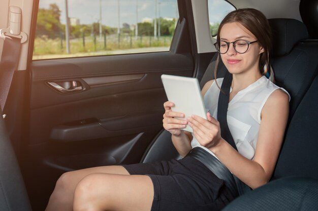 Jonge onderneemster met gadgetzitting in moderne auto