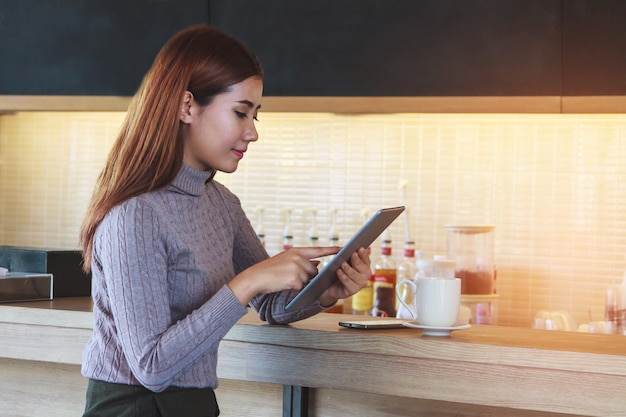 Jonge onderneemster met tablet in koffie