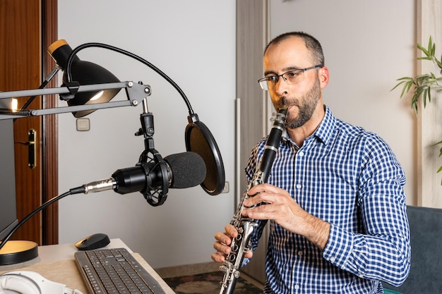 Jonge ondernemer die thuis klarinet speelt en muziek opneemt om het online te streamen met zijn computer