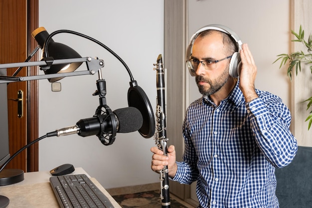 Foto jonge ondernemer die thuis klarinet speelt en muziek opneemt om het online te streamen met zijn computer