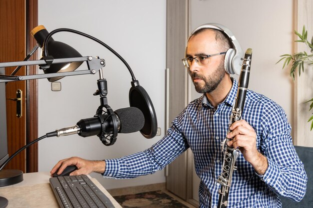 Jonge ondernemer die thuis klarinet speelt en muziek opneemt om het online te streamen met zijn computer