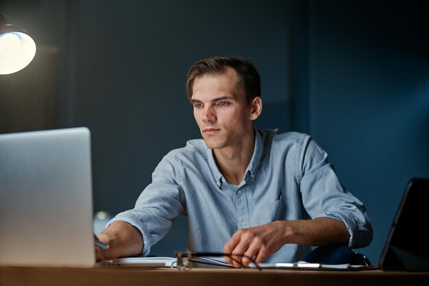 Jonge ondernemer werkt 's avonds laat enthousiast op een laptop