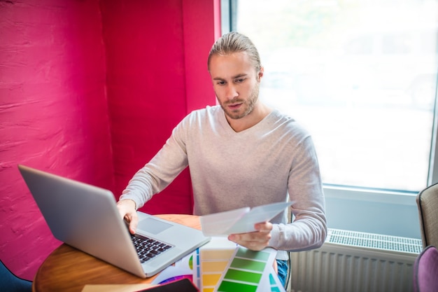 Jonge ontwerper die aan laptop in een restaurant werkt