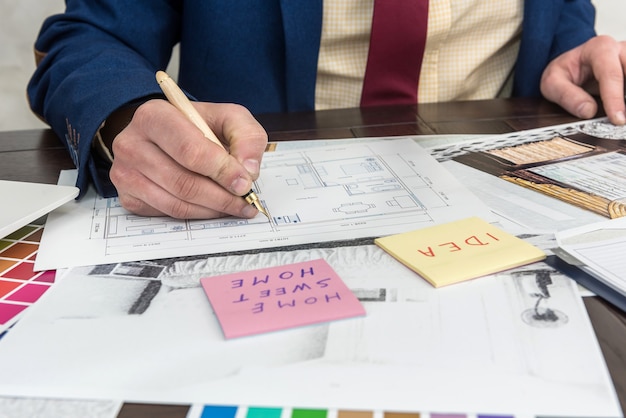 Foto jonge ontwerper werkt aan de kleurkeuze en reparatie van een modern appartement. schets platte en gekleurde patronen op het bureau op kantoor