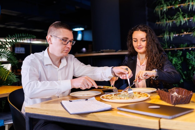 Jonge ontwerpers bespreken tijdens de lunch nieuwe projectideeën met hun partners in de vergaderruimte. mensen uit het bedrijfsleven bespreken een nieuw zakelijk project op kantoor.