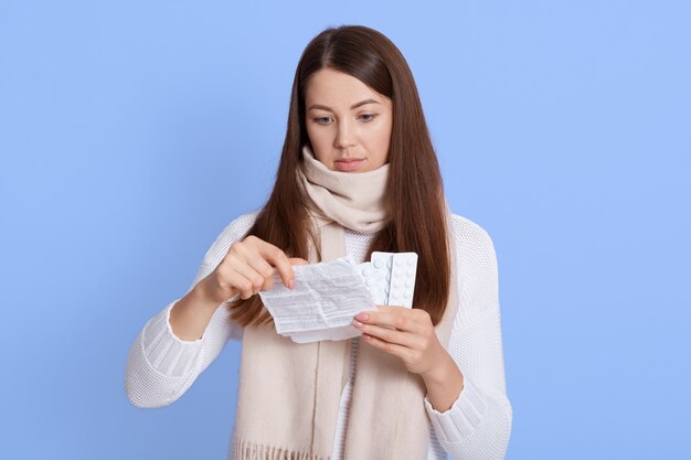 Jonge onwel donkerharige vrouw, gekleed in witte trui en sjaal