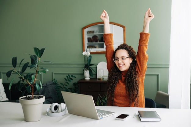 Jonge opgewonden gelukkige student winnaar succes met behulp van computer laptop thuis online winnen