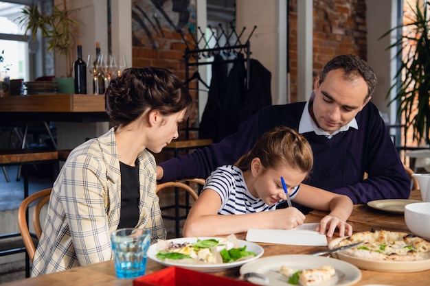 Jonge ouders die het huiswerk van hun dochter controleren. Er zijn een paar dingen die u moet corrigeren.