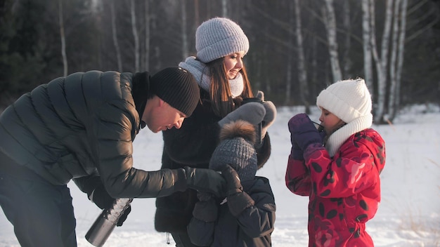 Jonge ouders met hun kinderen die buiten warme dranken drinken