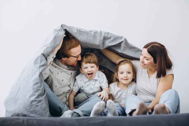 Jonge ouders met kinderen hebben in het weekend plezier in bed.