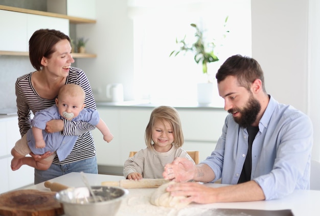 Jonge ouders spelen met kinderen in de keuken