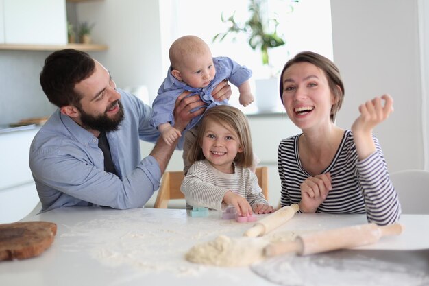 Jonge ouders spelen met kinderen in de keuken