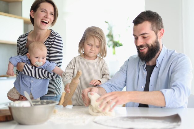 Jonge ouders spelen met kinderen in de keuken