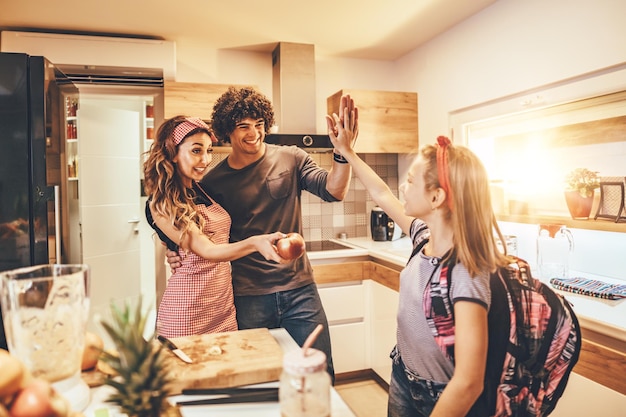 Jonge ouders sturen hun dochter naar school en geven haar een appel als tussendoortje.