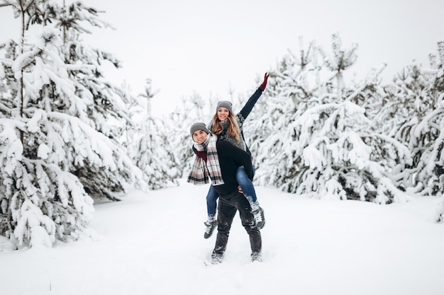 Jonge paar kaukasische man en vrouw meeliften rit op wintervakantie in besneeuwde bossen