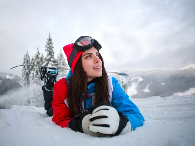 Jonge peinzende vrouw in de winter in sneeuwbos bovenop bergen