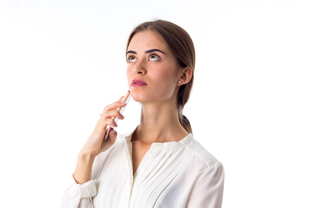 Jonge peinzende vrouw in witte blouse die haar roze mobiele telefoon op witte achtergrond in studio houdt