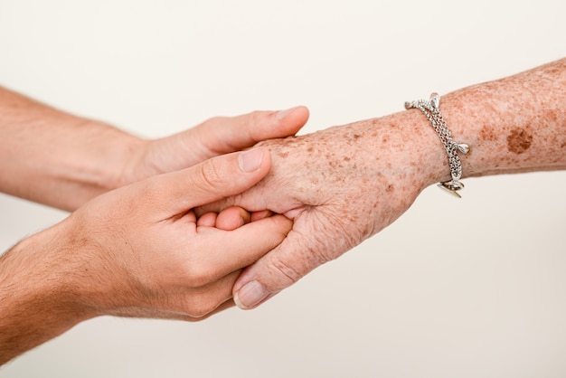 Jonge persoon die senior ouderen hand van dichtbij vasthoudt