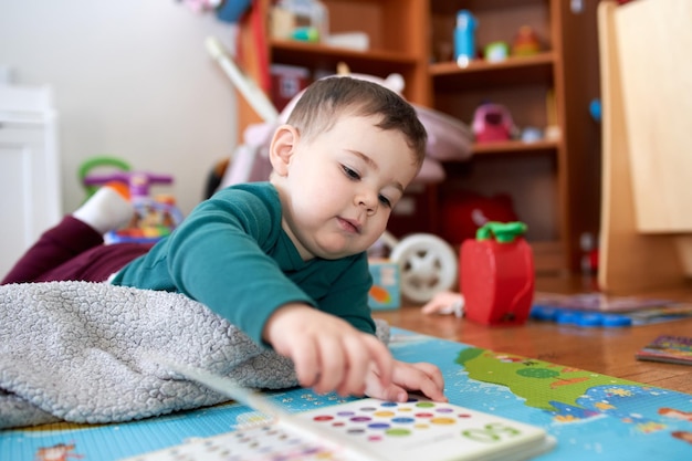 Jonge peuter kijkt naar boeken en speelt in zijn kamer
