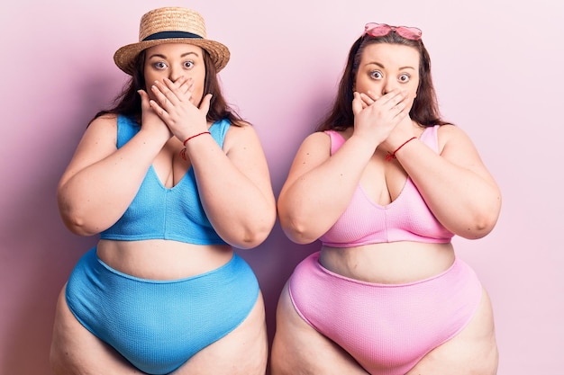 Jonge plus size tweelingen dragen bikini geschokt bedekkende mond met handen voor fout geheim concept