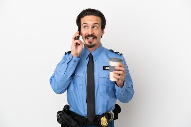 Jonge politieman over geïsoleerde achtergrond wit met koffie om mee te nemen en een mobiel?