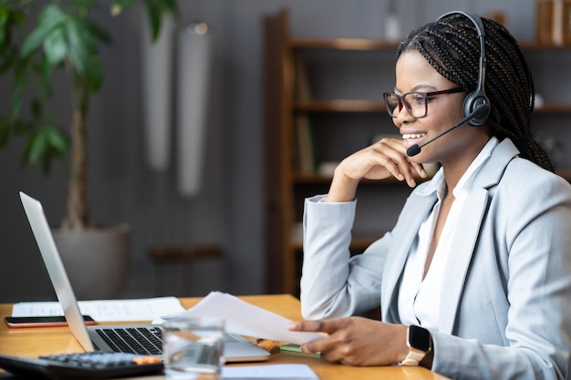 Jonge positieve afro-vrouw die draadloze headset gebruikt voor werken op afstand tijdens zwangerschapsverlof