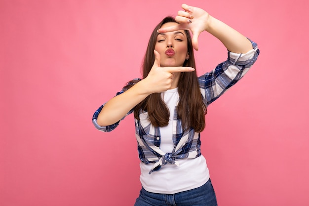 Jonge positieve, heerlijke, mooie brunette vrouw met oprechte emoties die een hipster geruit overhemd draagt