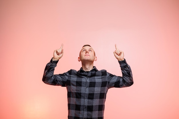 Foto jonge positieve lachende man in een geruit overhemd op een roze achtergrond plaats voor tekst