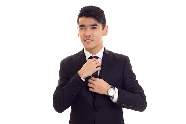 Jonge positieve man met zwart haar in wit overhemd en zwarte smoking met stropdas en duur horloge