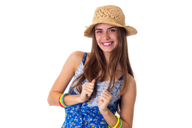 Jonge positieve vrouw in blauw T-shirt met gekleurde armbanden die lacht en haar lange haren aanraakt op een witte achtergrond in de studio