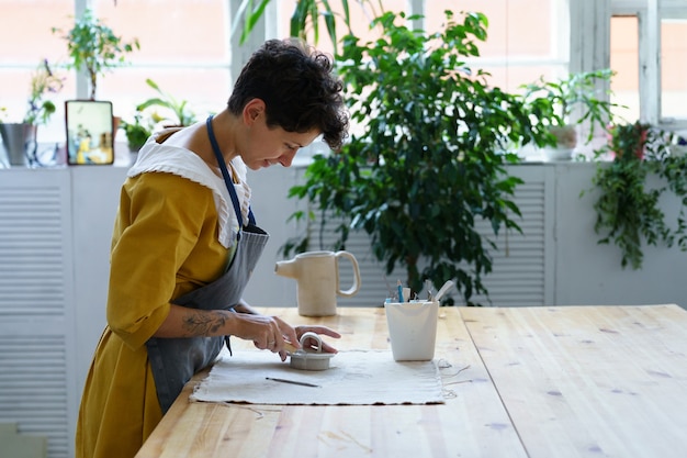 Jonge pottenbakkersdame keramische studio-eigenaar bereidt keukengerei voor op workshoples in creatieve studio