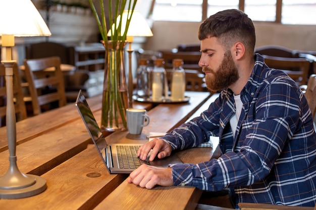 Jonge professional surfen op internet op zijn laptop in een café