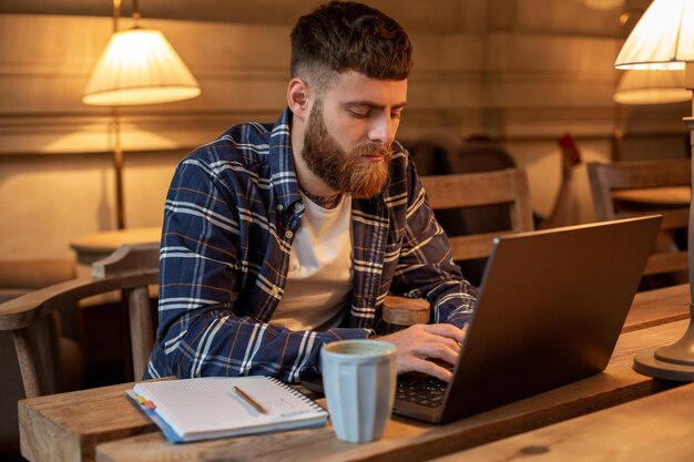 Jonge professional surfen op internet op zijn laptop in een café