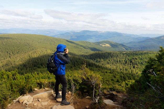 Jonge professionele reiziger met dslr-camera die buiten fantastisch berglandschap fotografeert