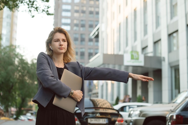 Foto jonge professionele vrouw die haast heeft met het liften van een taxi in het financiële district, maakt zich zorgen