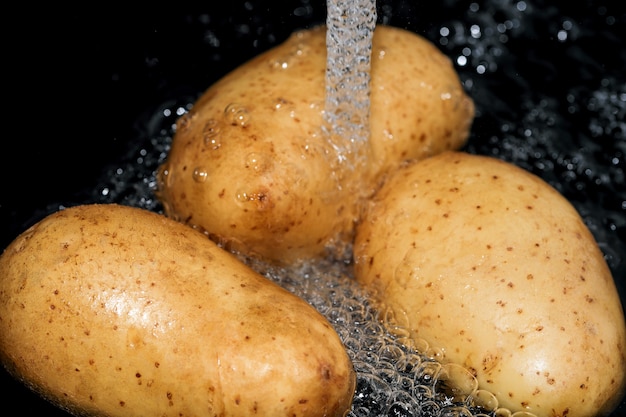Jonge rauwe aardappelen in hun schil worden gewassen in schoon water voordat ze close-up macrofotografie koken