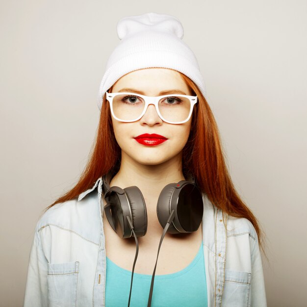 Jonge redhairvrouw die met hoofdtelefoons muziek luisteren.