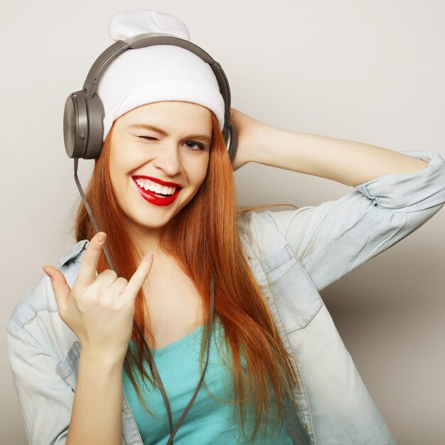 Jonge redhairvrouw die met hoofdtelefoons muziek luisteren.