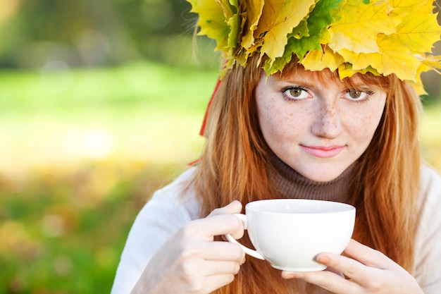 Jonge redhead tienervrouw in een kroon van esdoornbladeren