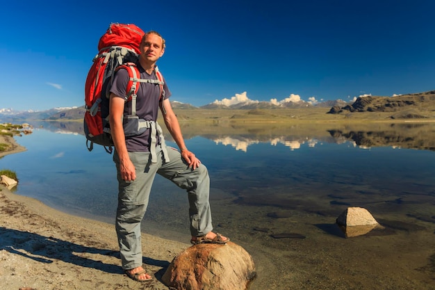 Jonge reiziger met een rugzak op de achtergrond van het meer en de bergen