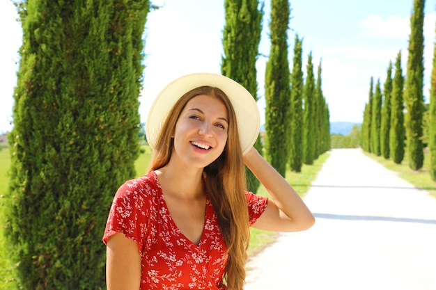 Jonge reiziger vrouw wandelen in cipressen lane op zonnige dag